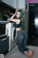 A woman sitting on the floor in front of a washing machine.