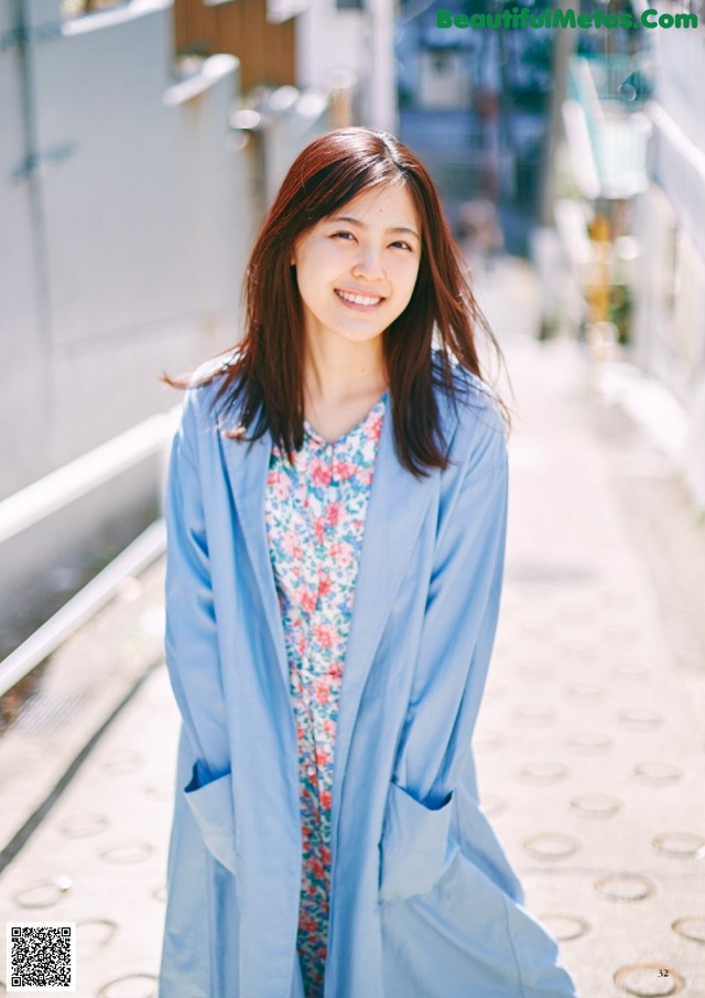 A woman in a blue coat standing on a sidewalk.