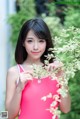 A woman in a pink tank top holding a plant.