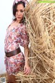 A woman standing next to a pile of hay.