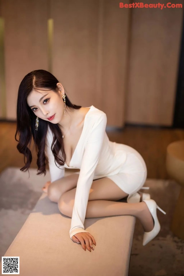 A woman in a white dress sitting on a bench.