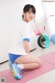 A woman sitting on a pink yoga mat in a living room.