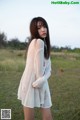 A woman standing in a field wearing a white dress.