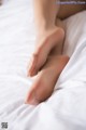 A close up of a woman's feet on a bed.
