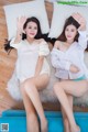 A couple of women laying on top of a blue couch.