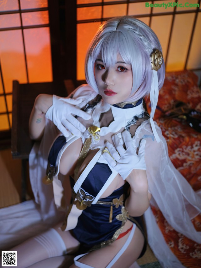 A woman in a white and blue outfit sitting on a bed.
