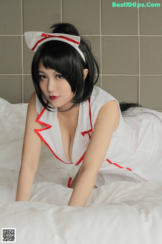 A woman in a white and red dress laying on a bed.